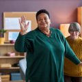 Waist up portrait of cheerful black senior woman dancing in retirement home and enjoying fun activities