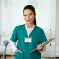 Portrait of young smiling nurse of rehabilitation center holding clipboard
